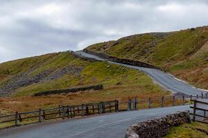 Winding road through hilly countryside with overcast sky in Yorkshire Dales. photo