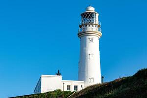 White lighthouse on a hill against a clear blue sky in Flamborough, England. photo