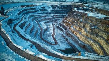 Aerial view of a vast open-pit mine with terraced layers under a blue sky. photo