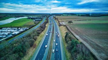 Aerial view of a busy highway with cars, surrounded by green fields and a cloudy sky. photo