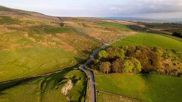 Aerial view of a winding road through lush green countryside with rolling hills under a soft evening sky. photo