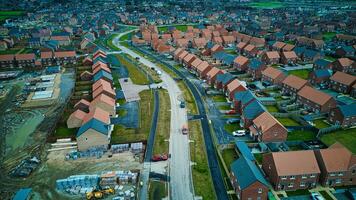 aéreo ver de un suburbano alojamiento desarrollo con en marcha construcción, exhibiendo el modelo de residencial calles y casas foto