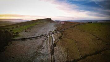 Aerial view of a tranquil countryside landscape at dusk with rolling hills and a winding path at Sycamore Gap, Northumberland, UK. photo