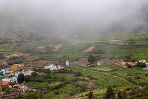 Misty rural landscape with green fields, scattered houses, and winding roads on a cloudy day Mountain landscape with blue sky and clouds in Tenerife. photo