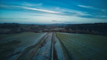 Aerial view of a tranquil countryside road at dusk with soft lighting and a serene sky. photo