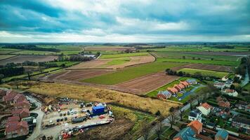 Aerial view of a rural landscape with farmland, houses, and roads under a cloudy sky. photo