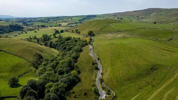 Aerial view of a winding road through green rolling hills in a rural landscape. photo