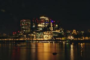 Night cityscape with illuminated buildings reflected on water surface. photo