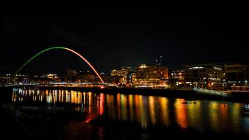 Night cityscape with a colorful arch bridge reflected in the water in Newcastle upon Tyne photo