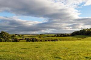 Serene countryside landscape with lush green fields under a dynamic cloudy sky. photo