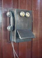 Antique old telephone hang on wooden wall photo