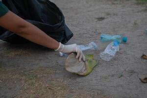 Cleanup volunteers woman picking leaves and plastic bottles into trash garbage bags,the concept of a clean natural environment photo