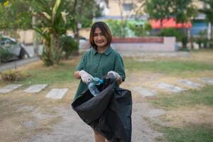 Cleanup volunteers woman picking leaves and plastic bottles into trash garbage bags,the concept of a clean natural environment photo