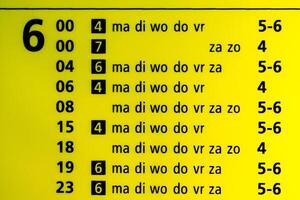 Train departure table for 6am, yellow illuminated. Text is displaying the weekdays mon, tue, wed, thu, fri, sat and sun photo