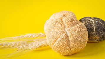 two rolls of bread and wheat on a yellow background photo