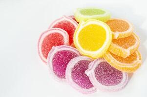 a pile of colorful gummy candies on a white surface photo