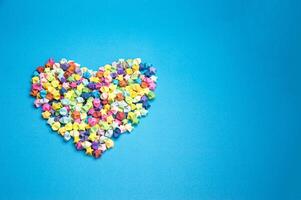 Paper folded into the shape of a multi-colored 5-pointed star, on a blue background. Arranged in the shape of a heart photo