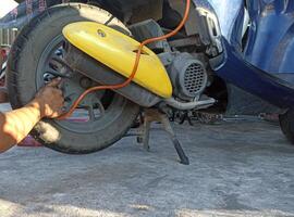 un motocicleta mecánico es agregando aire a un neumático. foto