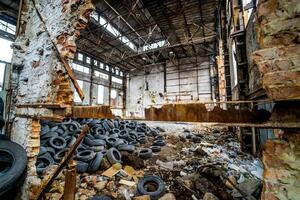 Destroyed old factory with garbage and a pile of used rubber tyres inside. Tires that are no longer suitable for use on vehicles in a damaged plant. photo