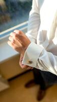 Groom wearing cufflink. Handsome young groom going to his wedding photo