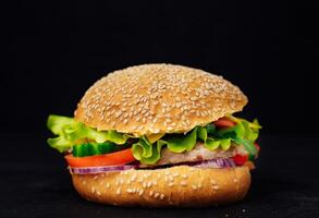 Tasty and appetizing hamburger. Fresh appetizing hamburger isolated on black background photo