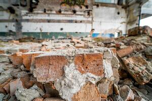 Debris of bricks in ruins of the destroyed factory building inside. Pieces of stones are crumbling from demolished walls of a house. Close-up photo