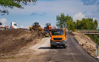 Industrial dumper trucks working on highway construction site, loading and unloading gravel and earth. heavy duty machinery activity photo