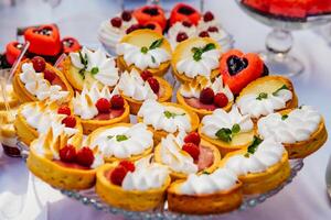 dulce mesa con Fruta pasteles con crema y dulzura en fiesta antecedentes. delicioso caramelo bar. Boda caramelo bar Servicio foto