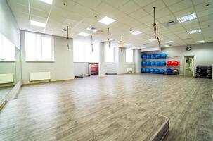 Beautiful spacious gym for fitness trainings with sport equipment. Fitness yoga and pilates light hall with aerobic balls at the end of it. photo