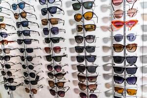 Sunglasses in the shop display shelves. Stand with glasses in the store of optics. photo