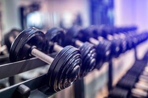 Rows of heavy iron dumbbells in the gym. Workout training and fitness gym concept. Sport equipment and tool theme. photo