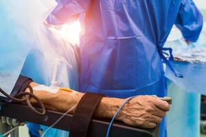 Restrainted patient on the operation table in surgery with a drip in a hand. Patient's hand with a sensor,Hand critically ill patients. IV fluids. Closeup. photo