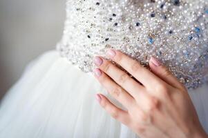 female hand touches the wedding dress of the bride with rhinestones in the waist. photo