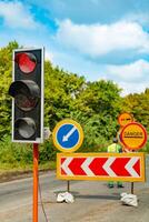 traffic-light shows a red color near the road in the daytime in warm weather on the background of road signs photo