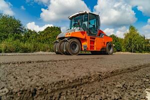 vibrating roller machine compacts asphalt using four hot wheels of rollers on the road. Close-up photo