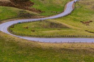 Winding country road through green hills, showcasing rural landscape and travel concept in Peak District, England. photo