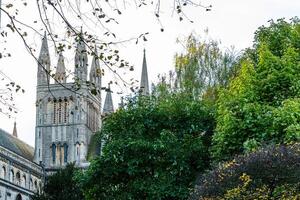 Scenic view of a historic cathedral peeking through lush green foliage under a clear sky in Peterborough, England. photo