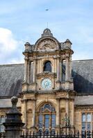 Elegant historical building facade with ornate clock under a blue sky with clouds in Oxford, England. photo