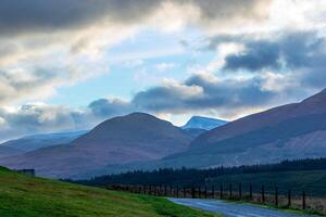 Serene landscape with rolling hills under a dynamic sky at dusk, showcasing nature's tranquility in Scotland. photo