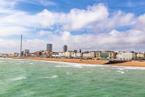 Brighton beachfront with calm sea, cloudy sky, and cityscape, suitable for travel and tourism themes. photo