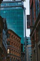 Urban cityscape with historic architecture contrasting against modern skyscrapers under a dusk sky in Manchester, England. photo