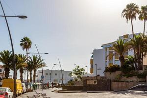 urbano parque con moderno naranja pérgola y circular diseños, con un persona sentado en el sombra, rodeado por palma arboles y ciudad edificios foto