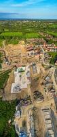 Aerial view of a construction site with machinery and partially built structures, surrounded by greenery. photo