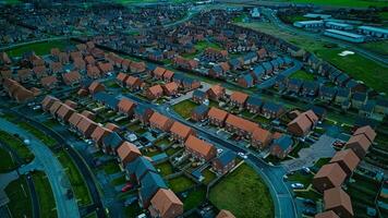 Aerial view of a suburban neighborhood at dusk with rows of houses and green spaces. photo