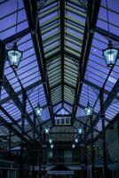 Elegant glass ceiling with vintage lamps in an indoor setting during twilight, showcasing architectural details and ambient lighting. photo