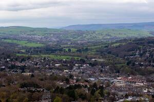 escénico ver de un lozano Valle con residencial areas y verde colinas debajo un nublado cielo en ilkley, Yorkshire foto