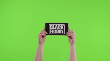 Black Friday advertisement inscription on paper sheet in womans hands on chroma key. Slow motion video