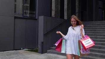 Pretty girl walking from centre mall with shopping bags, happy with purchase on Black Friday video