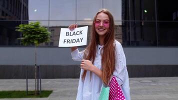 Cheerful girl showing Black Friday inscription text advertisement. Online shopping with low prices video
