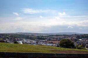 Scenic view of a town with houses and greenery under a blue sky with clouds in Whitby, England. photo